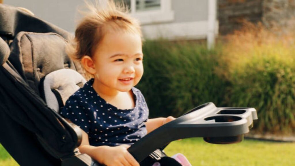 Child smiling in a colourful pediatric wheelchair in a park placing